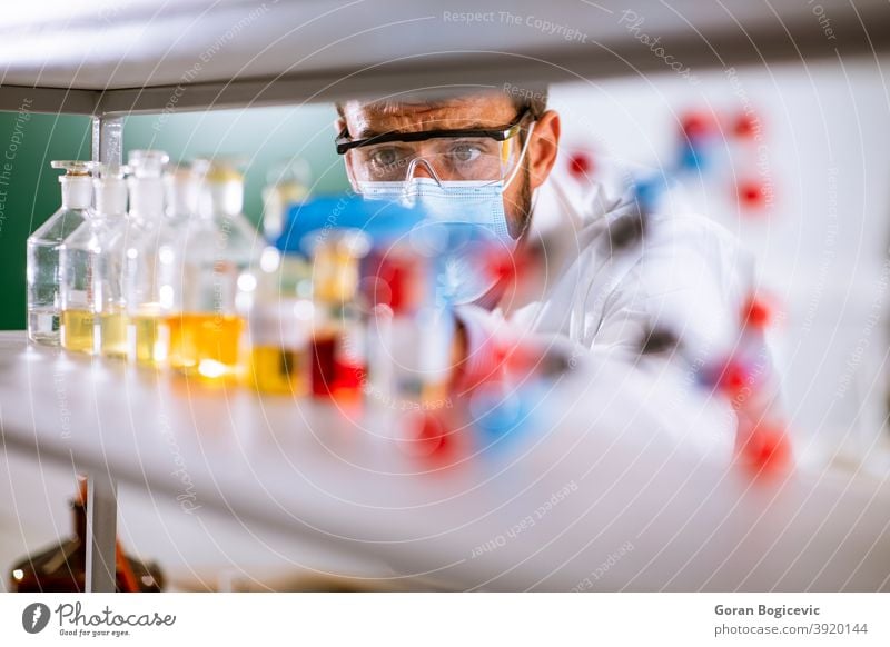 Young researcher with protective goggles checking test tubes education lab experiment laboratory science male scientist scientific man biochemist biotechnology