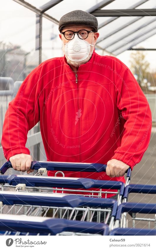 Man wears an mask while pushing a shopping cart new normal grandpa covid epidemic face mask 2019-ncov protective infection buyer one man only look groceries