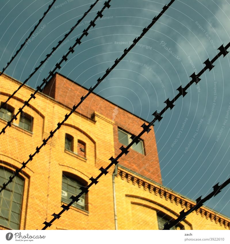 behind bars House (Residential Structure) Barbed wire Barbed wire fence Grating Brick facade Brick-built house Yellow Diagonal Line Fence Captured Protection