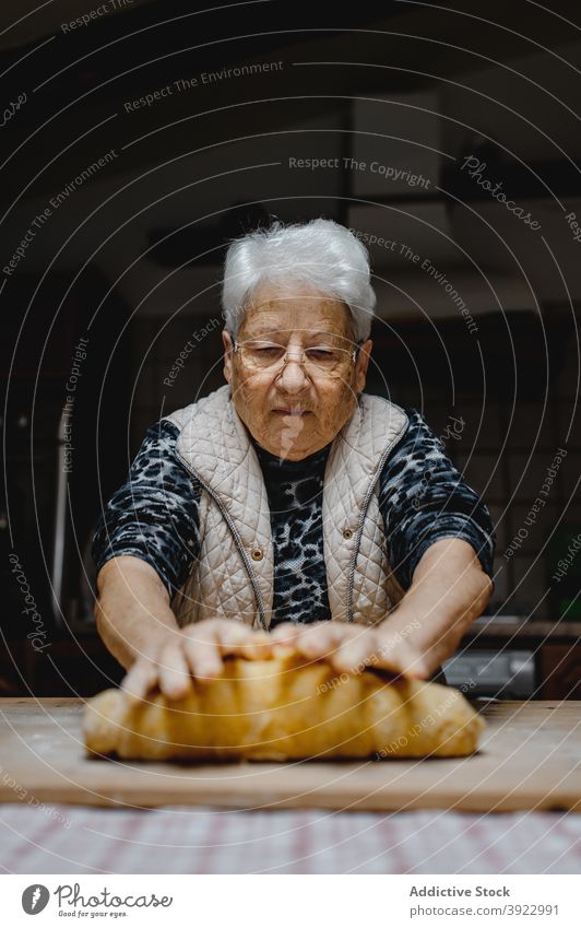 Aged woman kneading dough in kitchen cook homemade pastry tortellini italian food dumpling senior female aged tradition prepare raw ingredient table