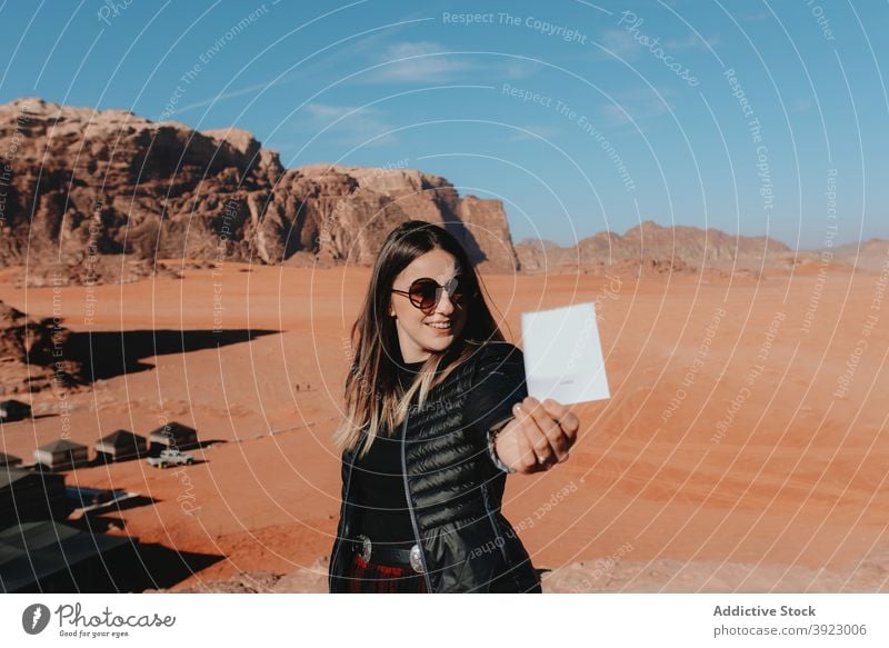 Cheerful woman standing with instant photograph in desert traveler cheerful old fashioned sandstone valley memory female wadi rum jordan tourism vacation happy