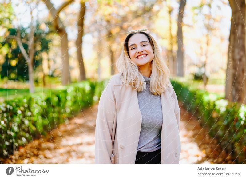 Young woman in coat in autumn park outfit smile stroll weekend casual young female cheerful happy optimist delight trendy pleasant glad positive lady stand