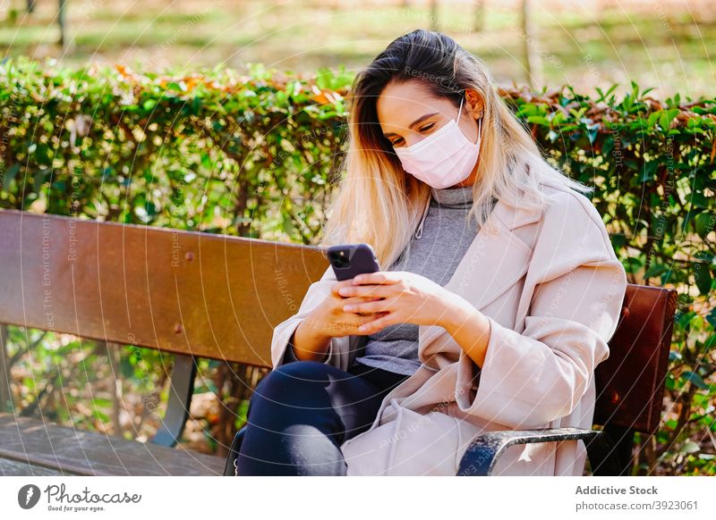 Cheerful woman in mask using smartphone in park coronavirus new normal protect speak cheerful female mobile phone device gadget call covid sit epidemic covid 19