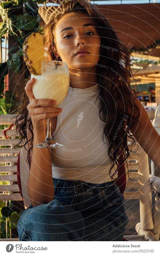Young woman drinking fruit beverage in cafe fresh chill summer terrace glass pineapple millennial brunette female young refreshment relax lifestyle tropical