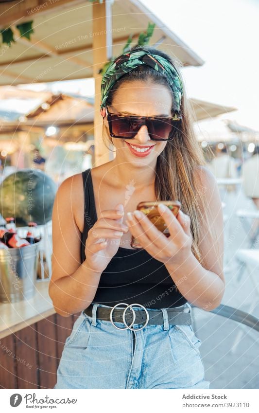 Happy woman browsing mobile phone in outdoor bar smartphone using summer tropical cheerful happy female sunglasses message lifestyle gadget rest device optimist
