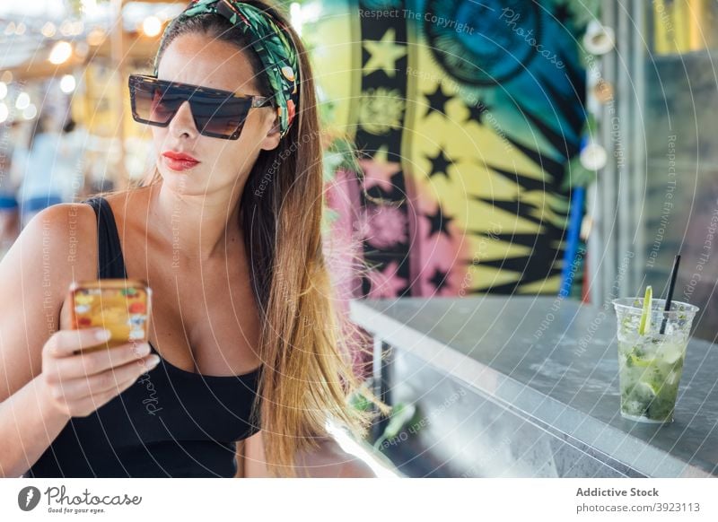 Woman browsing mobile phone in outdoor bar woman smartphone using summer tropical female sunglasses message lifestyle gadget rest device optimist online