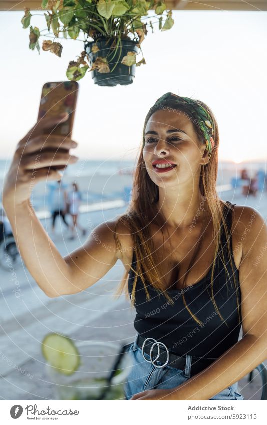 Happy woman taking selfie in bar smartphone using summer tropical cheerful browsing happy message lifestyle gadget rest device optimist smile mobile online