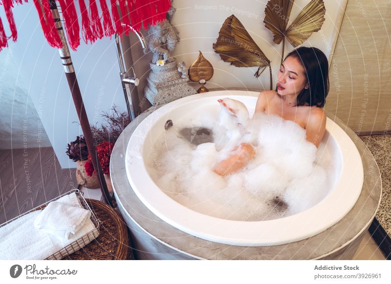 Young woman relaxing in bathtub with foam rest oriental spa wellness hygiene treat young asian female ethnic taiwan procedure healthy skin care wellbeing pamper