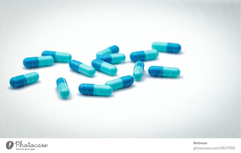 Selective focus on blue capsule pills. Group of capsule pills with shadow spread on white background. Pharmacy drugstore product. Healthcare and health insurance background. Pharmaceutical industry.