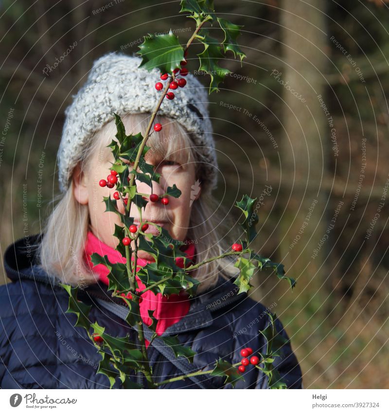 incognito ;-) - Portrait of a senior woman with long hair and cap hiding behind a holly branch Human being portrait Senior citizen Woman Gray-haired Cap Coat