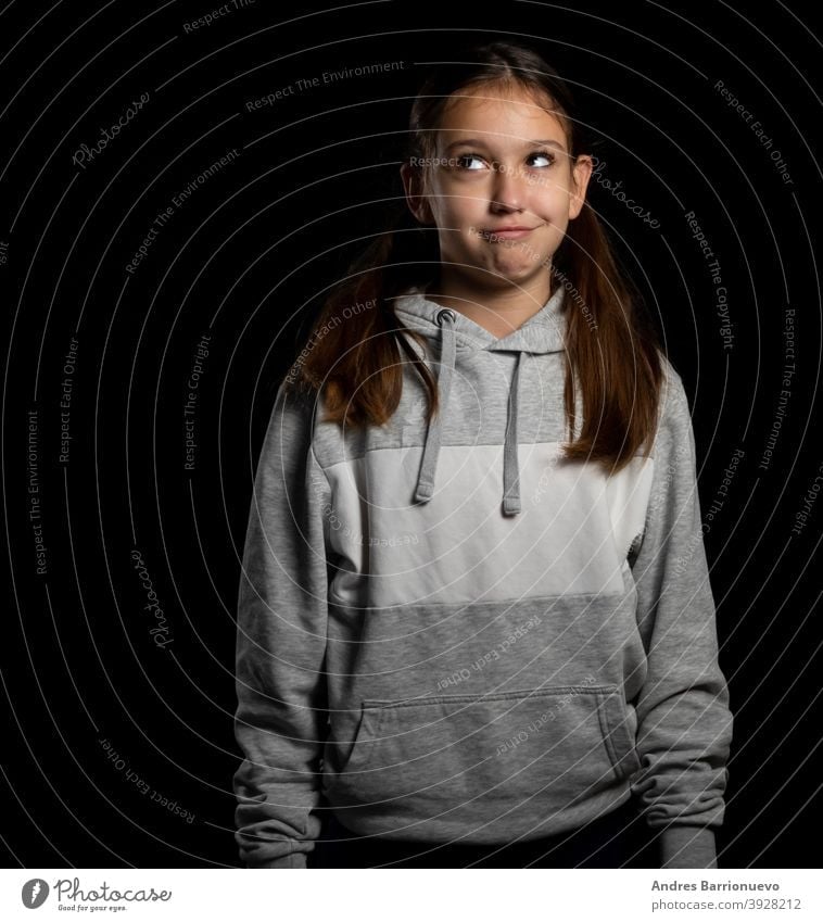 Beautiful little girl in a gray sweatshirt and with two pigtails looking up with funny attitude on a black background daughter joy positive child cute people
