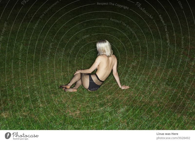 A topless girl is laying on the green grass. A gorgeous blonde girl is getting comfy on the ground while turning her sexy back for a pose. A flashlight makes this dark summer night reveal the secrets.