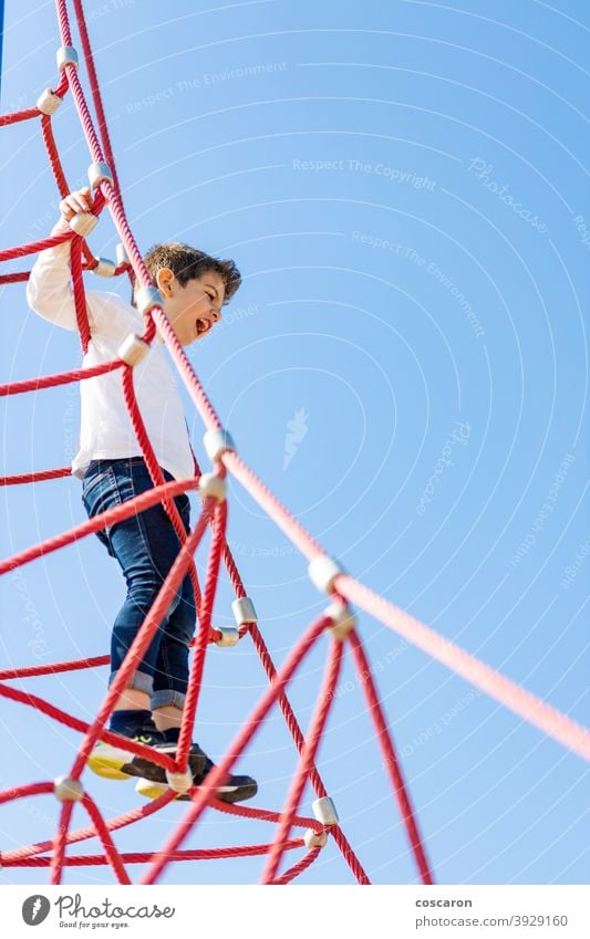 Funny boy climbing in a playground active activity adventure balance blue sky brave caucasian child childhood children climbing frame color colorful enjoying