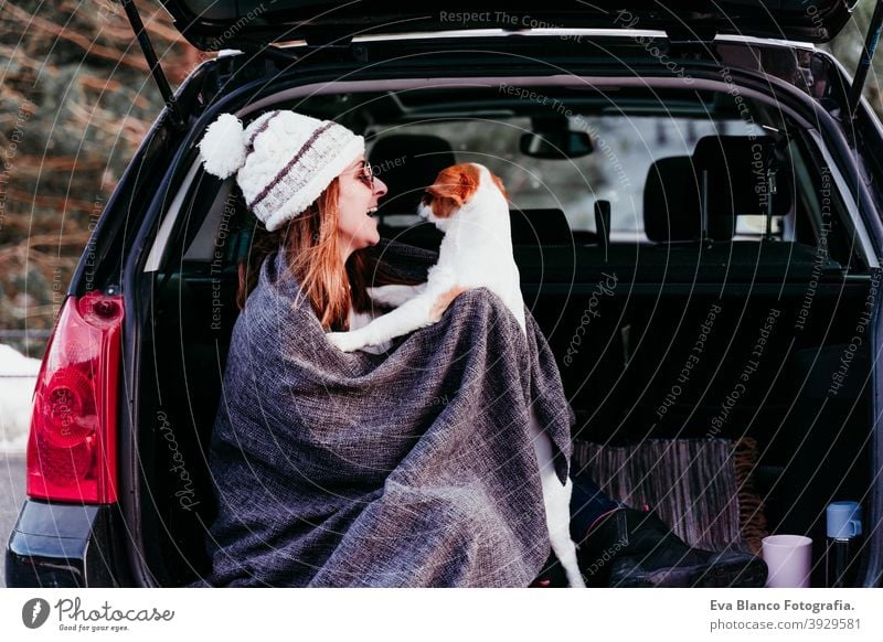 young woman and cute jack russel dog in car. Winter season, snowy mountain background blanket nature together wanderlust beauty active togetherness friends day