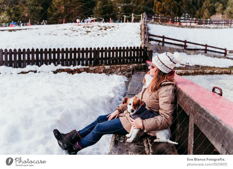 woman and cute jack russell dog enjoying outdoors at the mountain with snow. winter season travel lifestyle wanderlust traveling fun cold tress forest hug