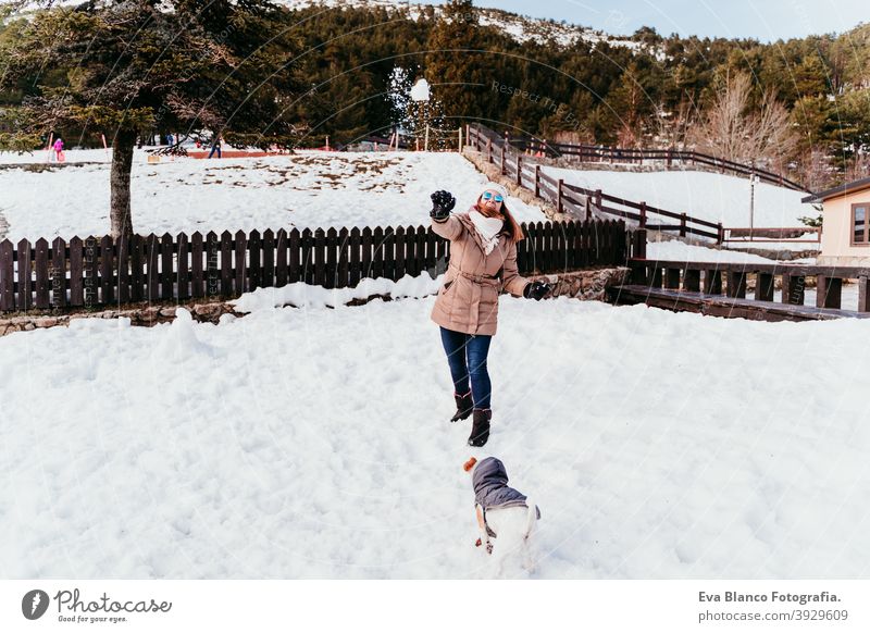 woman and cute jack russell dog enjoying outdoors at the mountain with snow. winter season travel lifestyle wanderlust traveling fun cold tress forest hug