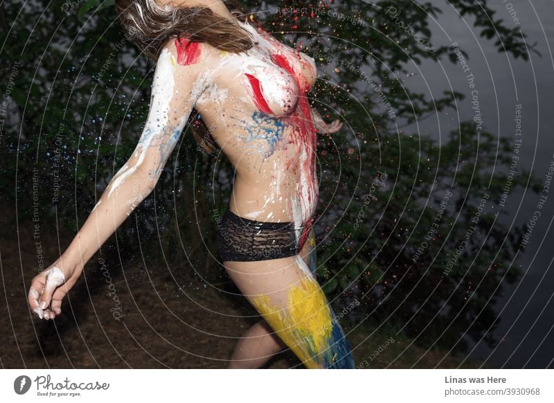 This is an image of a topless sexy girl being splashed with colorful body paint. Erotic photograph with a perfect girl and her sexy curves undoubtedly.