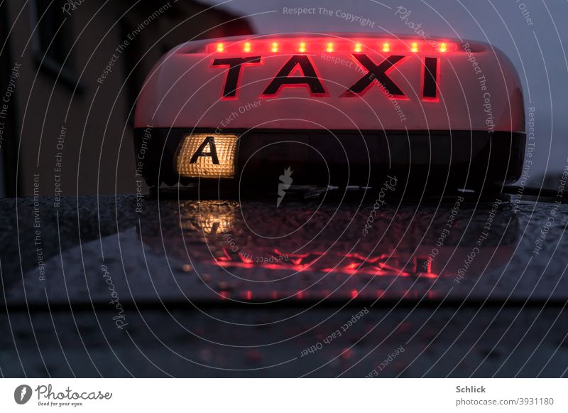Light on a taxi with red LEDs and reflection in the rain wet tin roof Taxi light Red Twilight raindrops Drops of water France Lorraine Close-up closeup