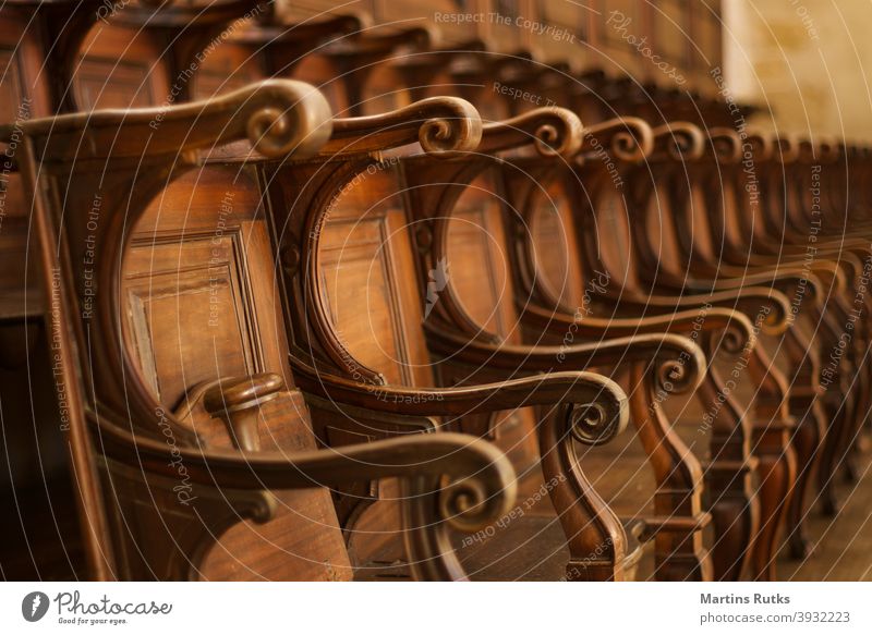 Empty rows of wooden chairs at old Convent, Castle. Curved fine wood details. seat empty auditorium court event vacant brown light architecture pattern religion