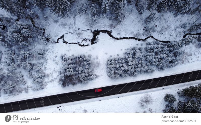 Aerial view with a drone of a road with a car driving through the forest in the winter time Aerial photograph drone photo Winter Street Driving Snow Forest