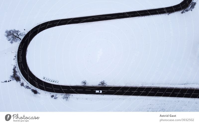 Aerial shot with a drone of a road curve with a moving car in winter Aerial photograph drone photo Winter Street Driving Snow Curve hairpin bend road bend curvy