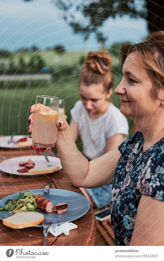 Family having a meal during summer picnic outdoor dinner in a home garden feast food man together woman barbecue table eating gathering people lifestyle
