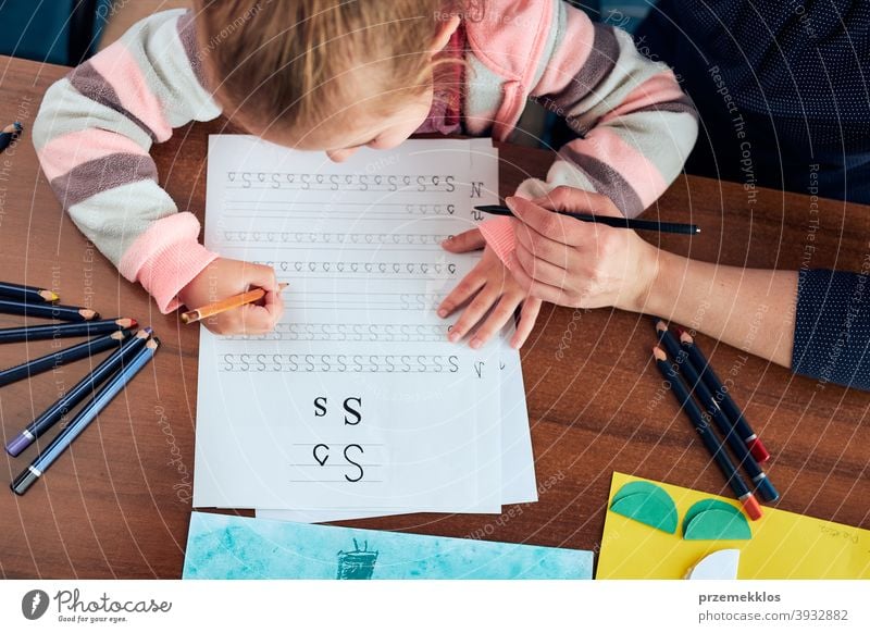 Little girl preschooler learning to write letters with help of her mother attention caucasian child childhood cute education educational fun home kid little