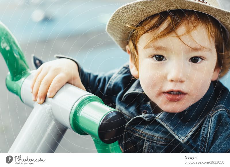 Young boy on a fitness training device in casual clothes and cool hat blue caucasian closeup cute exercise exerise machine face handle handlebar head shot