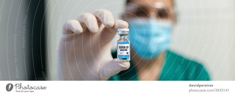 Female laboratory technician showing vial of coronavirus vaccine pharmaceutical laboratory unrecognizable medical medicine safety drug vaccination covid-19