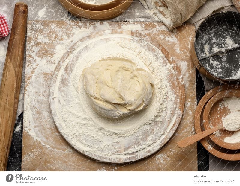 kneaded dough of white wheat flour lies on a round wooden board food fresh grain home homemade ingredient kitchen kneading making meal pasta pastry pie pizza