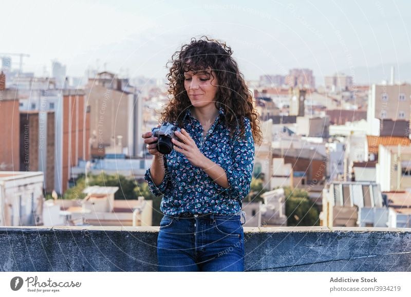 Smiling photographer on rooftop in city woman photo camera look through building cityscape female style gadget modern content urban smile memory moment lady
