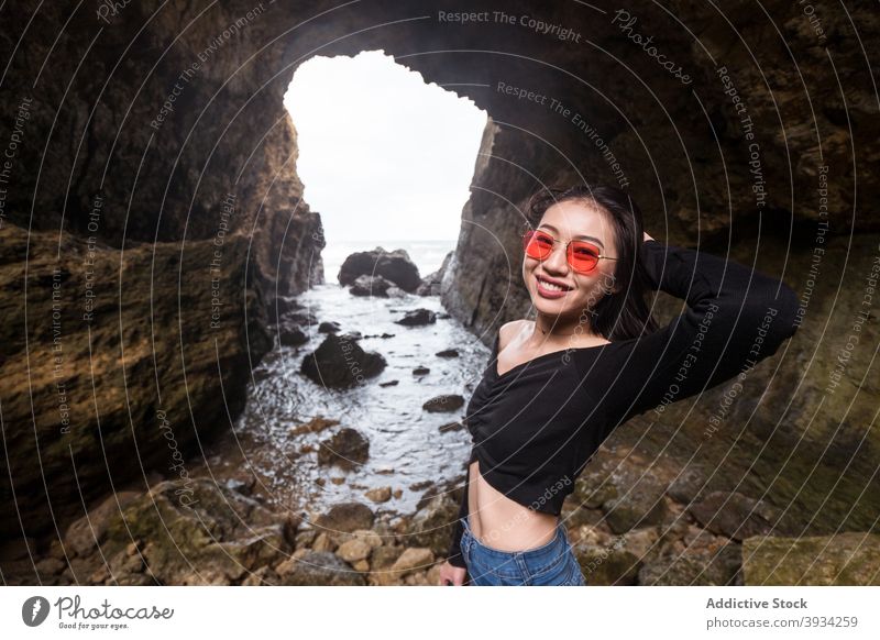 Happy woman standing in cave near sea explore traveler happy rock cheerful ocean nature young asian female ethnic rocky vacation taiwan journey tourism smile