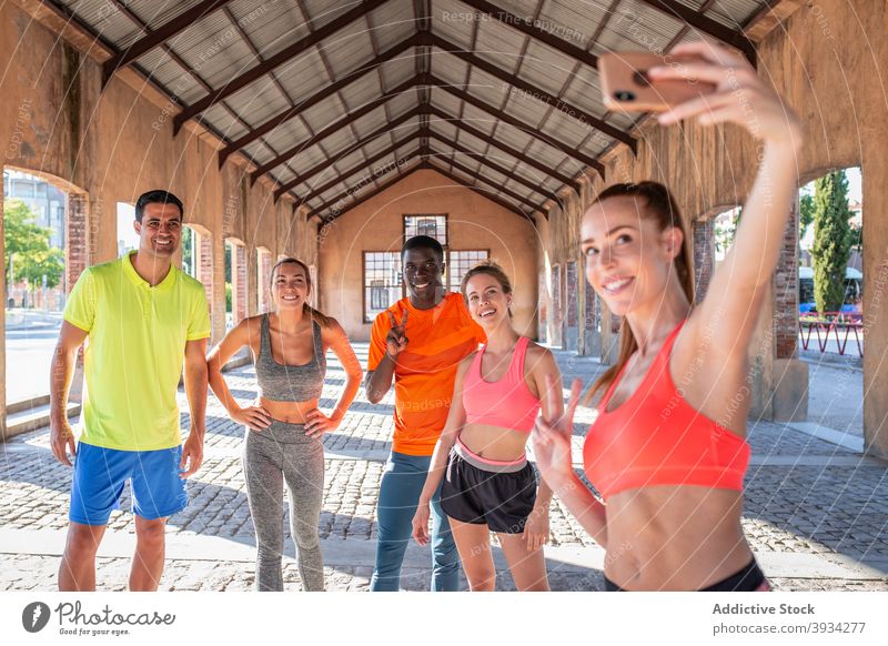 Company of cheerful sportspeople taking selfie during training in city team runner smartphone athlete self portrait summer multiethnic multiracial diverse black