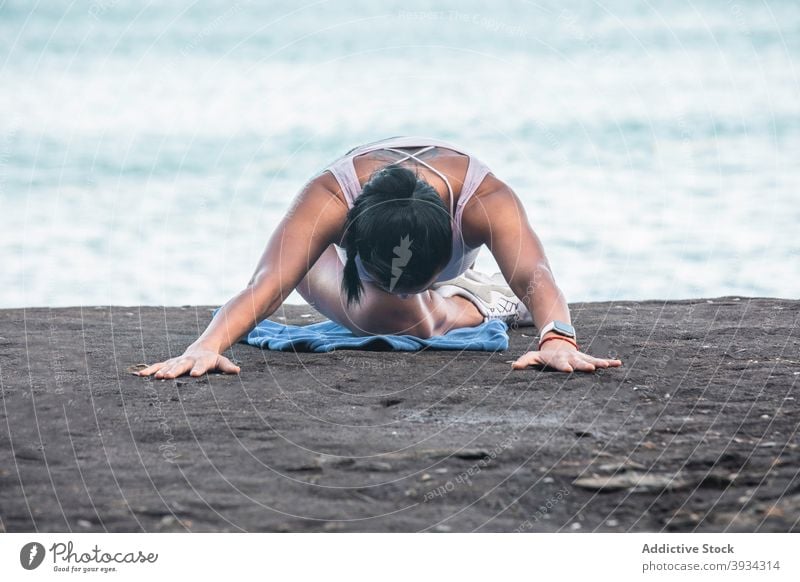 Woman doing yoga in Sleeping Swan pose on beach stretch woman sleeping swan pose asana seashore flexible summer female relax tranquil calm body wellbeing