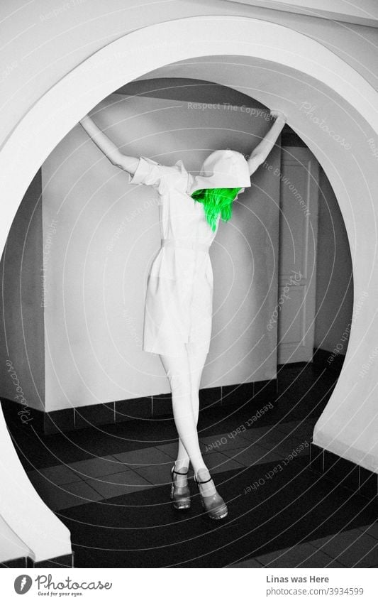 Green hair - don’t care. Even though the whole image is black & white. Latex fashion photoshoot featuring a female model with enormously long legs in high heels and a white raincoat with a hoodie.