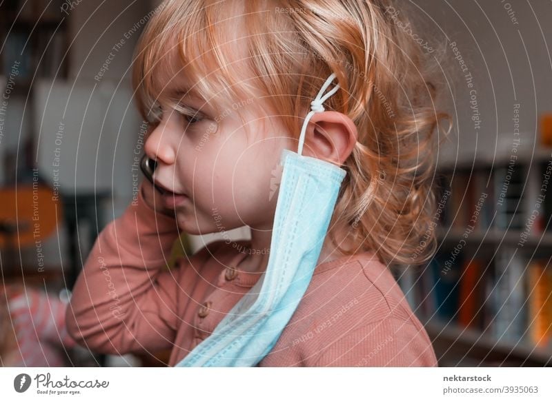 Child with Face Mask Hanging from Ear mask child kid female girl Indoor home at home caucasian face mask protective 2020 lockdown quarantine real life