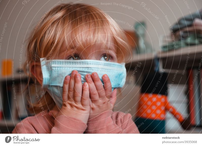 Child Covering Face with Mask surgical mask child kid face obscured female girl Indoor home at home caucasian face mask protective 2020 lockdown quarantine