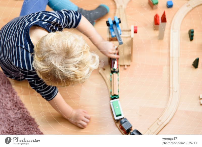 Little blonde boy playing with a wooden train on the floor Boy (child) little boy 4 years old Blonde Playing game wooden railway Railroad Child Infancy