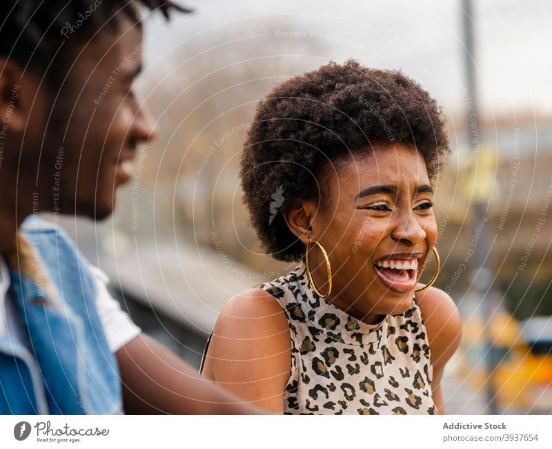 Cheerful black couple in trendy clothes standing on street cheerful hipster modern style laugh together afro young african american ethnic curly hair denim