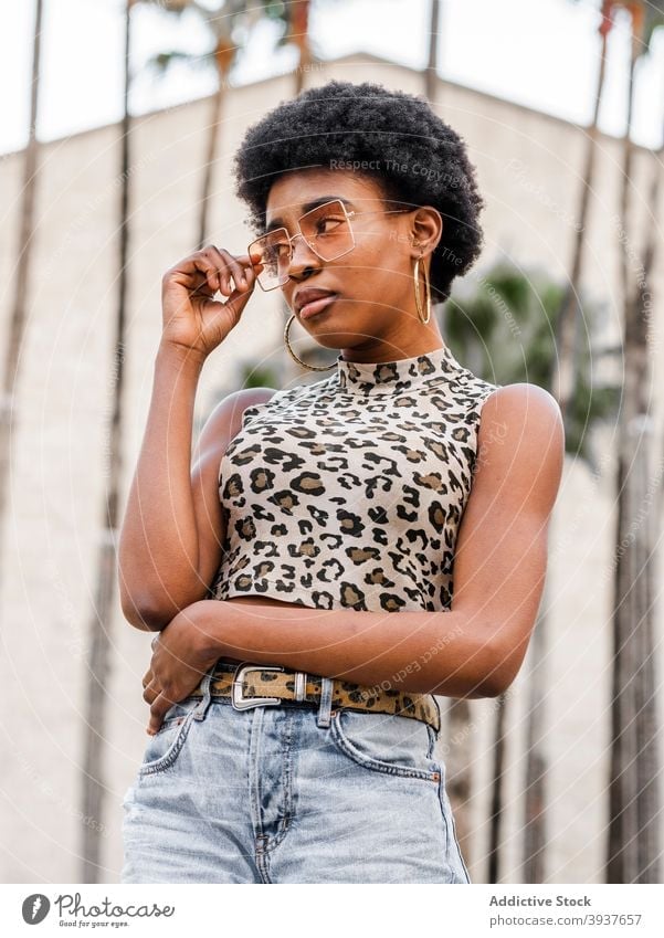 Young ethnic woman in trendy casual outfit style urban afro denim jeans print animal young confident female african american black crop top millennial