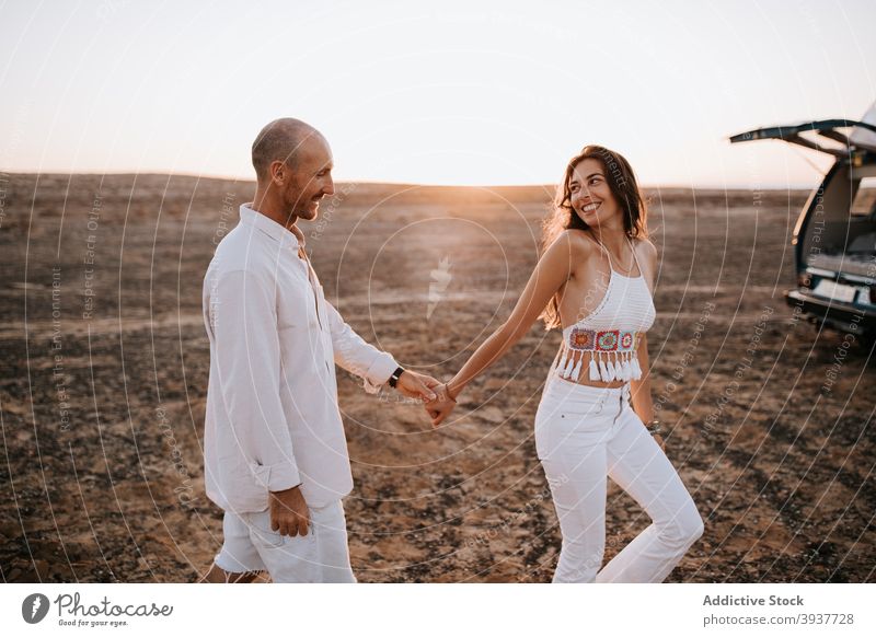 Carefree traveling couple holding hands in savanna sunset love summer vacation together relationship evening girlfriend walk holiday romantic tourism sundown