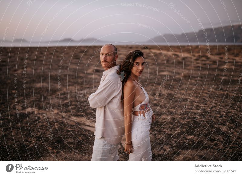 Couple standing back to back in nature couple love peaceful savanna evening twilight white outfit touch together boyfriend relationship tender calm girlfriend