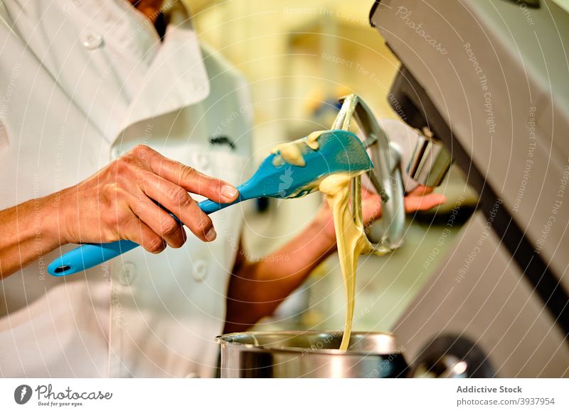Baker making dough in professional mixer woman pastry bakery confectionery beater prepare spatula kitchen cook food culinary chef process make occupation