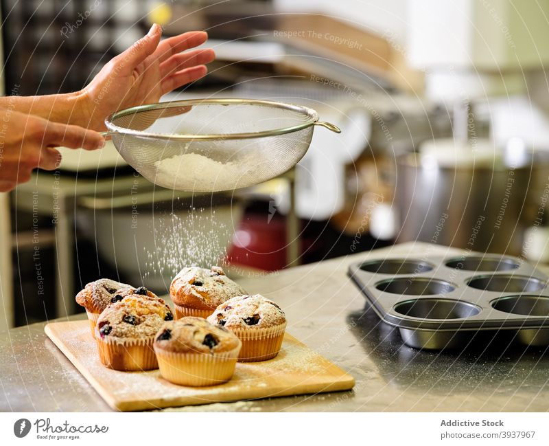 Chef sprinkling muffins with sugar powder pastry confectionery sprinkle sieve chef baked prepare kitchen professional dough culinary cook food cuisine work