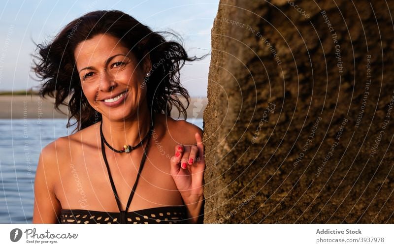 Smiling woman near rock at seaside summer beach vacancy smile enjoy cheerful sunset female algarve fuseta beach portugal vacation shore ocean bikini travel