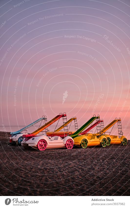 Colorful pedal boats with slides on beach near sea sunset coast shore sundown sand spain collection colorful dusk twilight holiday water summer evening sky