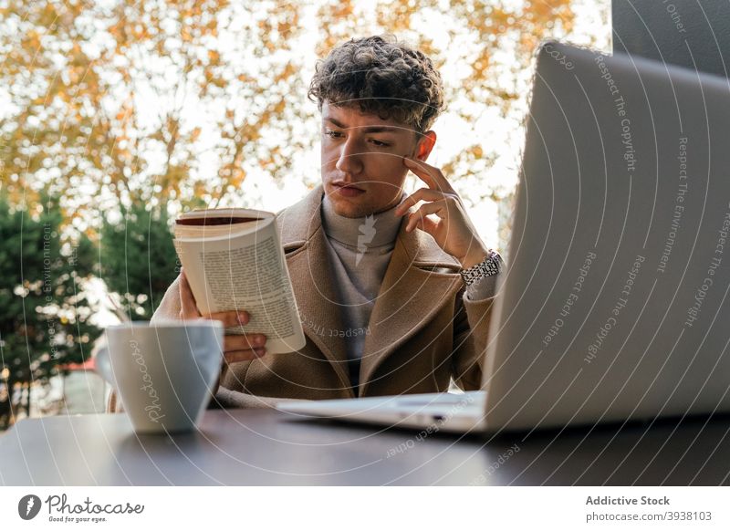 Focused man reading book in cafe serious thoughtful city pensive novel literature male table outfit interesting story young education casual relax fiction