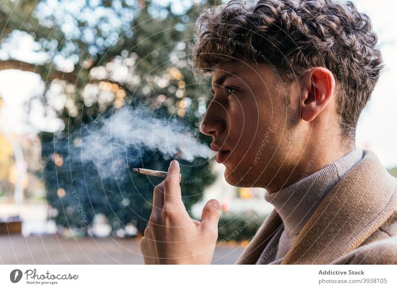 Confident man smoking cigarette in city smoke fume street style determine serious outfit male addict smoker bad habit unhealthy confident vapor trendy exhale