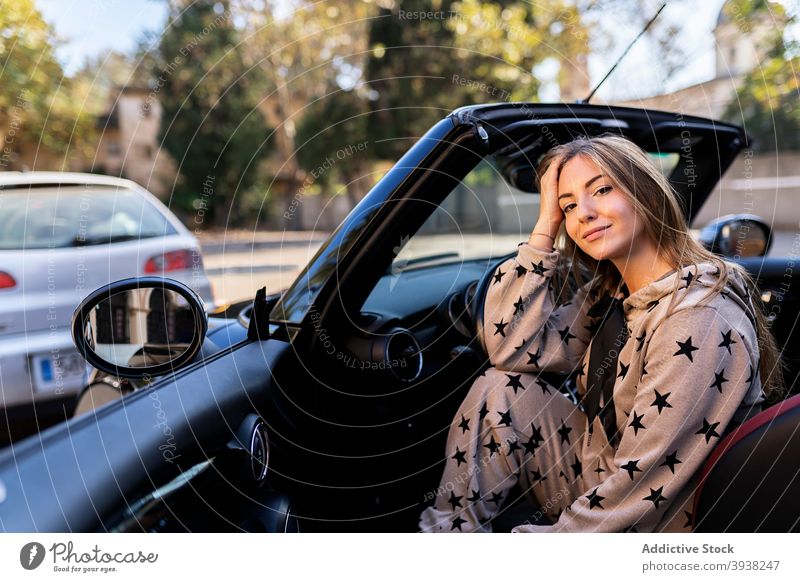 Young woman sitting in cabriolet in city car style convertible automobile driver modern urban young millennial female parked vehicle transport smile trendy lady