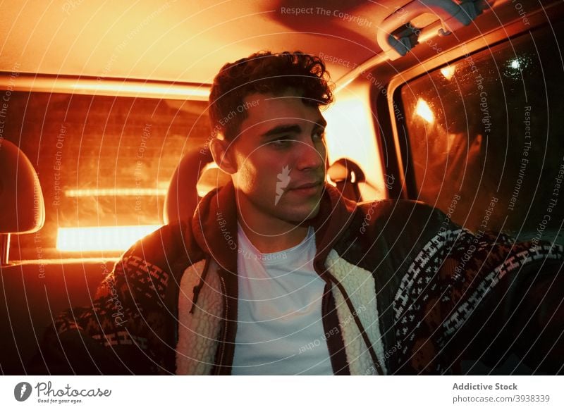 Stylish young man sitting in car with red neon light at night confident pensive illuminate thoughtful driver nightlife modern style male casual trendy